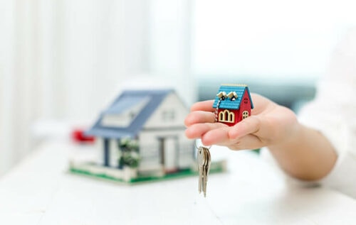 Imagem de uma pessoa segurando uma miniatura de casa e uma chave