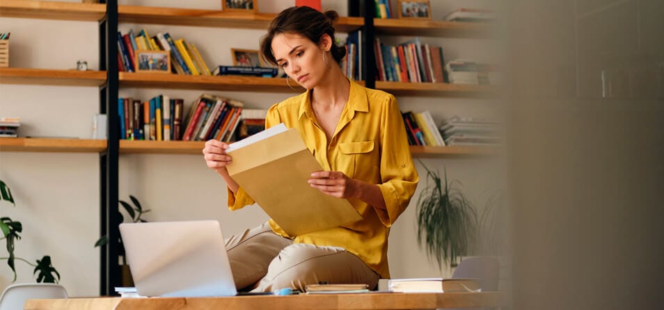 Foto de uma mulher sentada analisando alguns papeis que simbolizam os documentos para alugar imóvel