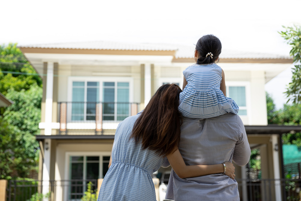 familia abraçada olhando para uma casa de costas