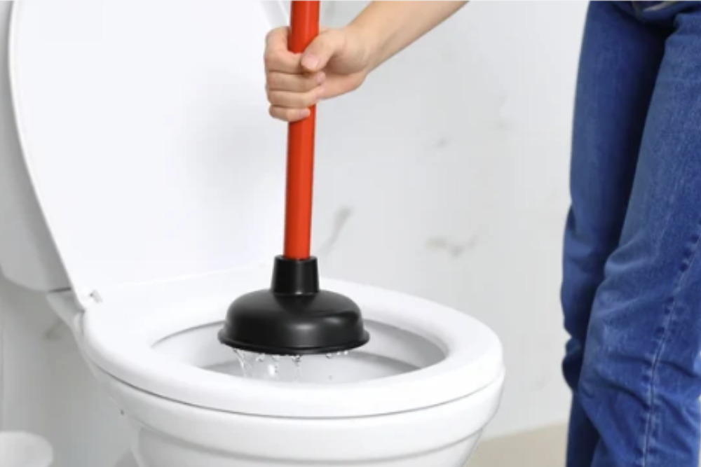 homem com desentupidor no vaso sanitário  